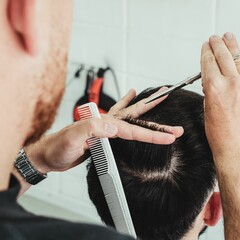 Closeup shot of a male barber working with a comb and an electric razor to style hair