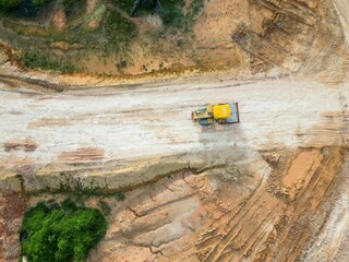 Aerial top view of a bulldozer cultivating a field of an oil palm plantation