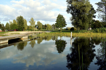 Molo z widokiem na jezioro oraz piasek i drzewa w oddali  © Klara