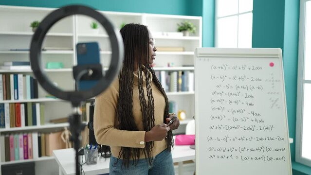 African woman recording teaching maths on magnetic board at library university