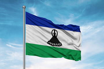 Lesotho national flag cloth fabric waving on beautiful sky Background.