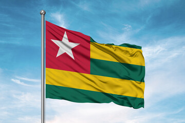 Fototapeta na wymiar Togo national flag cloth fabric waving on beautiful sky Background.