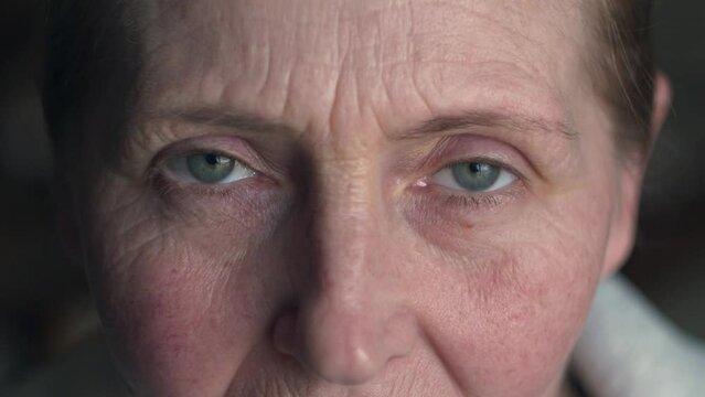 Face of middle aged Millennial woman with natural makeup and green-blue eyes. Beautiful mature female portrait with wrinkles on attractive face opening and closing her eyes.