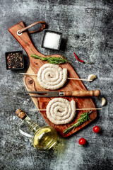 raw sausages spiral on skewers stone background
