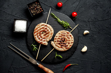 spiral sausages on skewers on a grill on a stone background
