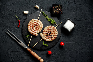 spiral sausages on skewers on a grill on a stone background