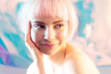 Young blond girl with short trendy haircut and modern makeup. Woman with glitters on facial skin and naked shoulders. Youth and beauty. Ad for skincare and make up cosmetics.