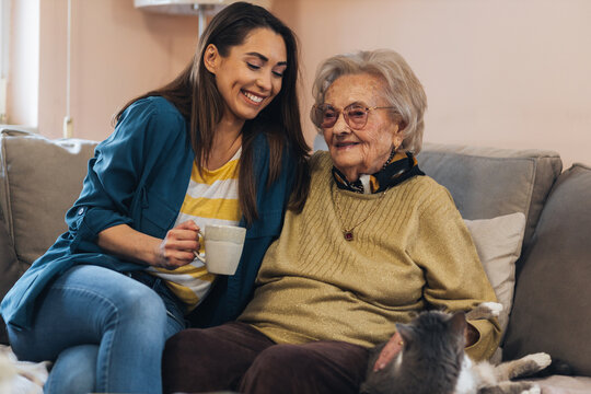 Young woman visiting her lovely grandma, drinking coffee together.