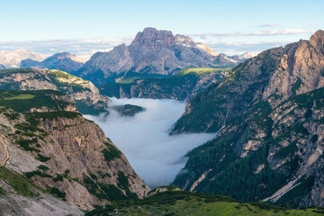 Fototapeta na wymiar Mountain canyon filled with clouds at sunrise in Dolomites, Alps, Italy. Italian mountain landscape