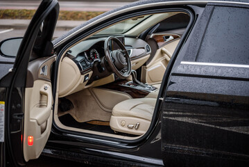 Side view of the open driver's door, mirror, dashboard of the car. Left front door. A new modern shiny parked black car. Interior luxury car with tinted glass standing at parking. Modern car exterior.