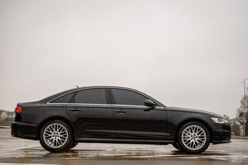 Black new modern business car is parked on the road. Automotive photography. Space for text....