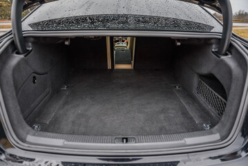 The car is parked with an open trunk. Rear view. Open empty trunk  modern sedan car. The car boot is open and ready for luggage loading. Empty space at the boot of Rental car service. Closeup.