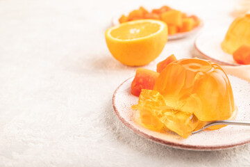 Papaya and orange jelly on gray concrete and orange linen textile. side view, selective focus.