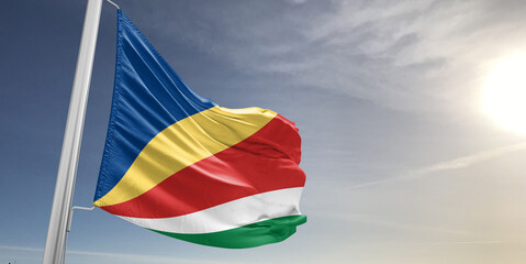 Seychelles national flag cloth fabric waving on beautiful sky grey Background.