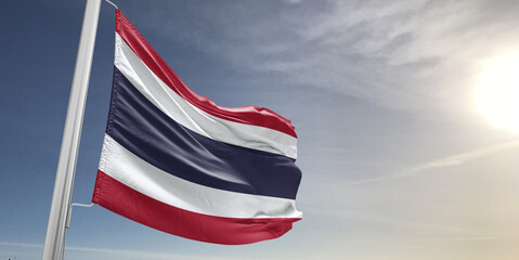 Thailand national flag cloth fabric waving on beautiful sky grey Background.