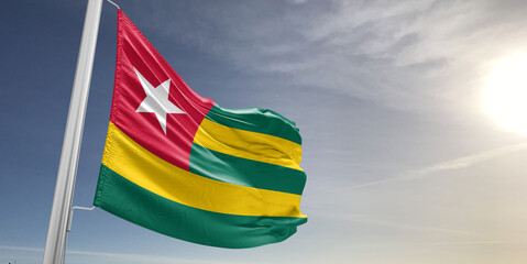 Togo national flag cloth fabric waving on beautiful sky grey Background.