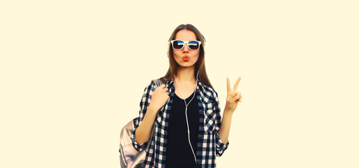 Portrait of cool teenager girl in headphones listening to music blowing her lips on white background