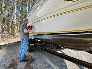 Caucasian man using a portable hand buffing tool on a power boat hull