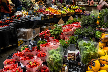 Strawberries and herbs at the market with other fruits and vegetables in the background