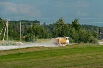 A dump truck is working on a sand quarry against the background of a forest. A truck is driving...