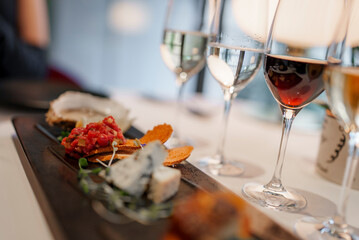 Closeup of wineglasses with various delicious appetizers served in plate on dining table at luxurious restaurant in modern hotel, luxury travel concept for tourists