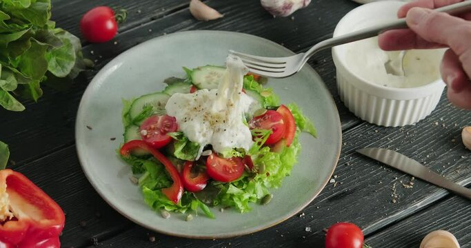 Person eating salad with fresh vegetables with stracciatella cheese on top, eating mozzarella cheese with fork, healthy salad with leaves and tomato cherries, 4k video footage