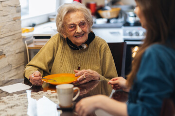 Senior woman eating soup with her caregiver.