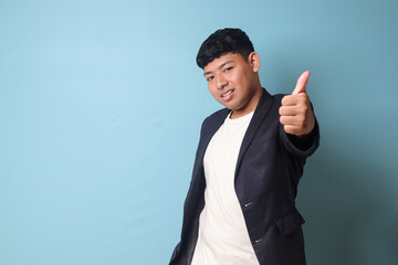 Portrait of young Asian business man in casual suit with happy expressions with thumb up gesture. Isolated image on blue background