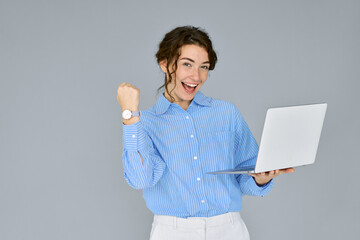 Young happy excited business woman executive holding laptop computer raising fist in yes gesture...