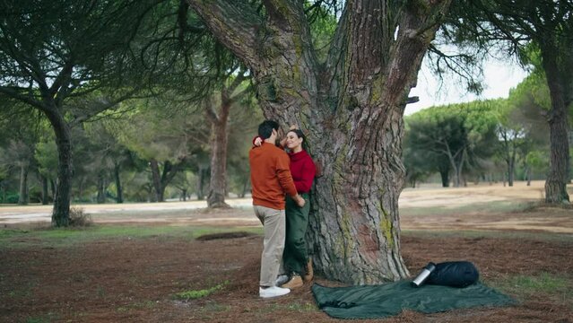 Couple standing leaning tree hugging. Cute pair talking cuddling on nature park.