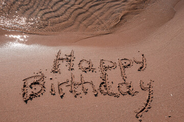 Happy birthday written on the sand beach