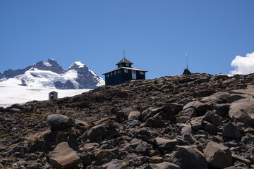 View of the wooden refuge built high in the rocky mountains.	Tronador hill peak in the background. 