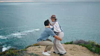 Cheerful couple dancing ocean view. Man lifting attractive woman on sea shore. - Powered by Adobe