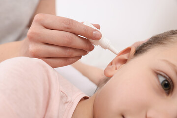 Obraz na płótnie Canvas Mother dripping medication into daughter's ear, closeup