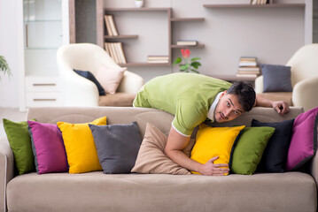 Obraz premium Young man with a lot of pillows sitting on the sofa