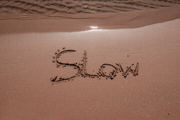 slow mindfulness concept written on sand