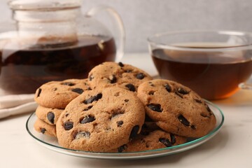 Delicious chocolate chip cookies and tea on white marble table, closeup