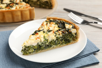 Piece of delicious homemade spinach quiche on table