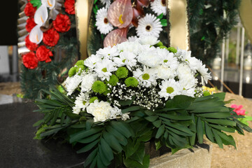 Obraz na płótnie Canvas Funeral wreath of flowers on granite tombstone in cemetery