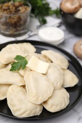 Delicious dumplings (varenyky) with tasty filling, butter and parsley on white table, closeup