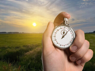 Man holding timer in meadow at sunset, closeup. Space for text