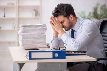 Naklejka premium Young male employee and too much work in the office