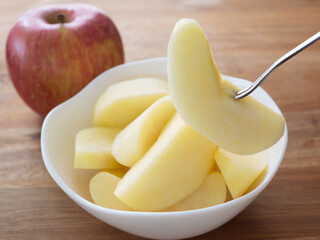 カットしたりんごをフォークで食べる