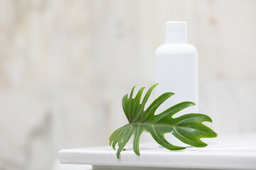 Skin care concept with white bottle and palm leaves on tropical background.