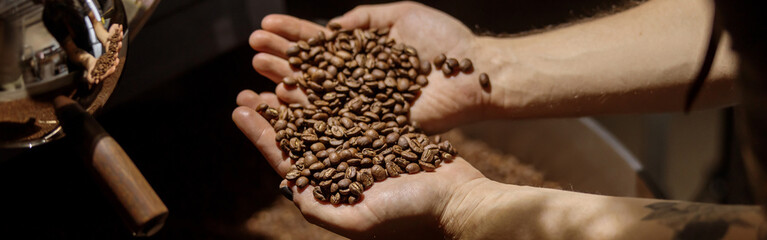 Male hands holding freshly roasted coffee beans