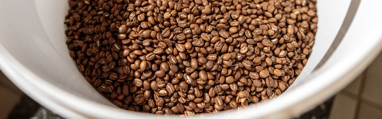 White plastic bowl with roasted coffee beans