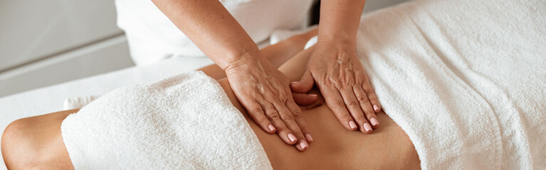Female client receiving stomach massage in spa salon