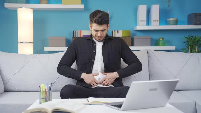 Young man with pancreatic cancer suffering from stomachache at home, writhing in pain. Young man suffering from stomach ache and suffering from pancreatic cancer.