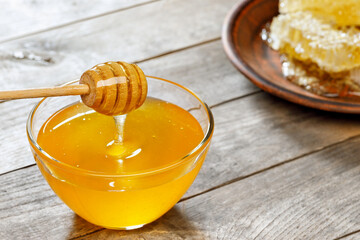 glass bowl of honey with honeycomb on table