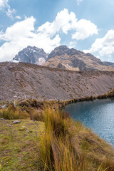Fototapeta na wymiar Photos of the tranquil turquoise lake and admiring the snow-capped Ausangate mountain peaks on a sunny day in Peru.